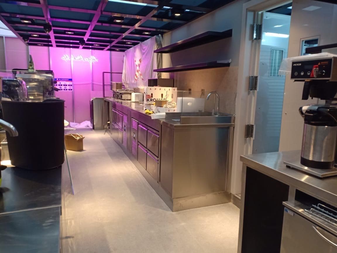 Cafe back-of-house counter run with stainless worktops, undercounter refrigeration and coffee equipment, Dubai